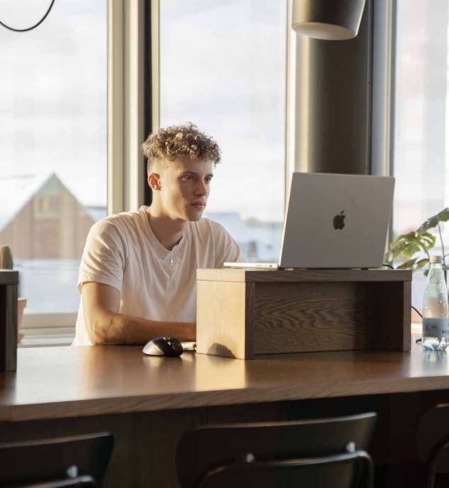 iværksætter som arbejder ved brunt bord på en macbook