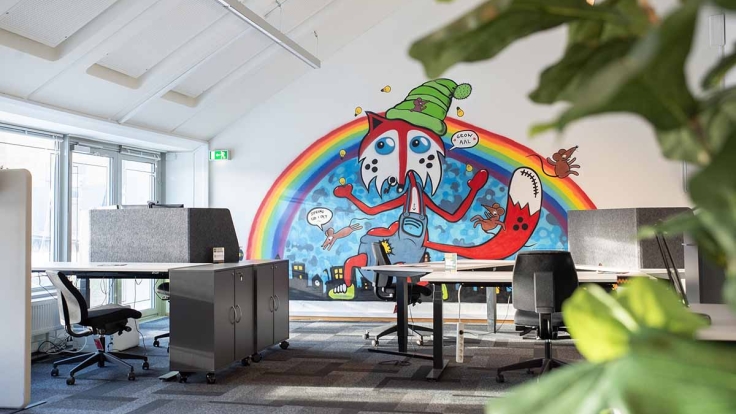 The delightful coworking area decorated with a mural on the wall by artist Johnny Hefty..